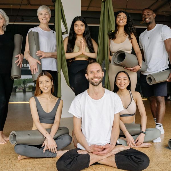 A diverse group of people of different ages smiling during a yoga class.